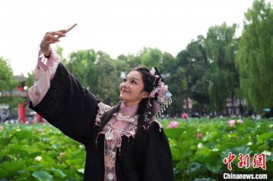 6月19日，時(shí)值一年畢業(yè)季，四川大學(xué)望江校區(qū)荷花池裡的荷花盛開，成為了畢業(yè)生們的打卡聖地，吸引了眾多畢業(yè)生拍照留念。圖為畢業(yè)生在荷花池邊拍照留念。中新社記者 安源 攝